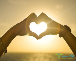 Sunset heart hands - a silhouette of someone making a heart shape with their hands against a beautiful sunset, symbolizing love and care in health and wellness, with the logo of Rejeune MD Wellness & Aesthetics at the bottom.